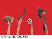 Руки зомби с древней книгой, мечом, человеческим черепом и топором на красном фоне. Празднование Хэллоуина. Стоковое фото, фотограф Pixel_shot / Фотобанк Лори