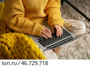 Красивая молодая женщина с теплым жёлтым пледом сидит на полу и пользуется ноутбуком в гостиной. Крупный план. Стоковое фото, фотограф Pixel_shot / Фотобанк Лори