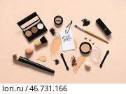 Композиция с декоративной косметикой, кистями для макияжа и ярлыком со скидкой на цветном фоне. Стоковое фото, фотограф Pixel_shot / Фотобанк Лори