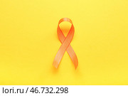 Оранжевая лента на жёлтом фоне. Месяц осведомлённости о рассеянном склерозе. Стоковое фото, фотограф Pixel_shot / Фотобанк Лори