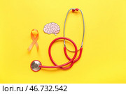 Бумажный мозг со стетоскопом и оранжевой лентой на желтом фоне. Месяц осведомленности о рассеянном склерозе. Стоковое фото, фотограф Pixel_shot / Фотобанк Лори