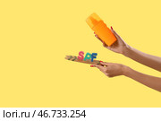 Женские руки с солнцезащитным кремом и буквами SPF на мини-серфборде на желтом фоне. Стоковое фото, фотограф Pixel_shot / Фотобанк Лори