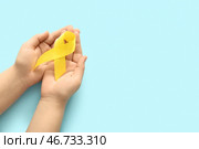 Женские руки с жёлтой лентой на синем фоне. Концепция саркомы. Стоковое фото, фотограф Pixel_shot / Фотобанк Лори