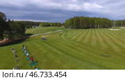 Golfers hitting golf shot with club on course while on summer vacation, aerial. Стоковое фото, фотограф David Kashakhi / Фотобанк Лори