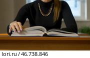 Woman sitting at the table leafing through the book. Стоковое фото, фотограф David Kashakhi / Фотобанк Лори