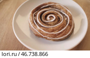 Close-up of sweet puff rolls with honey and white glaze lying on the white plate and rotating on the wooden round board. Стоковое фото, фотограф David Kashakhi / Фотобанк Лори