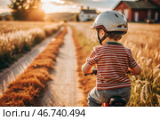 A cheerful little boy rides a bicycle in a helmet outdoors. A happy child is engaged in an active sport. Protection. Life insurance and child safety. Стоковое AI-изображение, AI-художник Photojuli / Фотобанк Лори