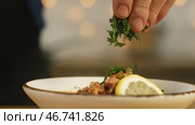 Close-up of some person's hand adding greens at the bowl with solyanka. Стоковое фото, фотограф David Kashakhi / Фотобанк Лори