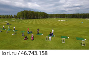 Golfers hitting golf shot with club on course while on summer vacation, aerial. Стоковое фото, фотограф David Kashakhi / Фотобанк Лори