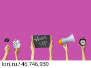 Руки, держащие будильники, речевой облачный знак, мегафон и доска с текстом "ВСТАВАЙ" на фиолетовом фоне. Стоковое фото, фотограф Pixel_shot / Фотобанк Лори