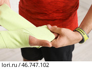 Зрелый мужчина с реабилитационным терапевтом обматывает запястье на белом кирпичном фоне, крупным планом. Стоковое фото, фотограф Pixel_shot / Фотобанк Лори