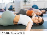 Sporty young woman doing yoga with group in studio, performing hamstring and low back stretching Ardha Pawanmuktasana. Стоковое фото, фотограф Яков Филимонов / Фотобанк Лори