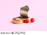 Открытая консервная банка с рыбой в соусе и помидорами на розовом фоне. Стоковое фото, фотограф Pixel_shot / Фотобанк Лори