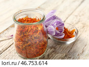 Банка и чаша с сушенными нитями шафрана и крокусами на белом деревянном столе. Стоковое фото, фотограф Pixel_shot / Фотобанк Лори