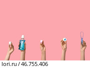 Женские руки с моделями зубов, устной водой, зубной нитью и скребком для языка на розовом фоне. Стоковое фото, фотограф Pixel_shot / Фотобанк Лори