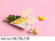 Стаканы вкусного лимончелло и тарелка с нарезанным лимоном на розовом фоне. Стоковое фото, фотограф Pixel_shot / Фотобанк Лори