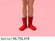 Ноги молодой женщины в красных вязанных носках на розовом фоне. Стоковое фото, фотограф Pixel_shot / Фотобанк Лори