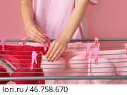 Женщина вешает чистое белье на сушилку на розовом фоне, крупным планом. Стоковое фото, фотограф Pixel_shot / Фотобанк Лори