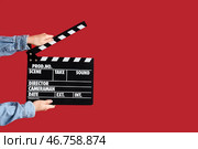 Женские руки с хлопушкой для фильма на красном фоне. Стоковое фото, фотограф Pixel_shot / Фотобанк Лори