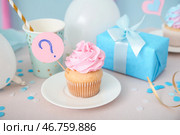 Вкусный кекс с подарочной коробкой и украшениями на столе на фоне голубого фона. Концепция вечеринки по раскрытию пола ребенка. Стоковое фото, фотограф Pixel_shot / Фотобанк Лори