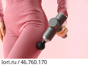 Спортивная молодая женщина массирует бедро перкуссионным массажером на розовом фоне, крупный план. Стоковое фото, фотограф Pixel_shot / Фотобанк Лори