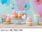 Вкусные капкейки с чашками и украшениями на столе на фоне синего цвета. Концепция вечеринки по случаю раскрытия пола ребёнка. Стоковое фото, фотограф Pixel_shot / Фотобанк Лори