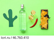 Бумажный кактус, деревянный поднос с начос, чили, бутылка и рюмки текилы на зеленом фоне. Стоковое фото, фотограф Pixel_shot / Фотобанк Лори