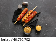 Доска с вкусными корн-догами и мисками с горчицей на черном фоне. Стоковое фото, фотограф Pixel_shot / Фотобанк Лори