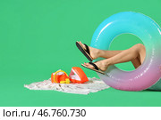 Молодая женщина с надувным кругом, полотенцем и наушниками на зеленом фоне. Концепция летних каникул. Стоковое фото, фотограф Pixel_shot / Фотобанк Лори