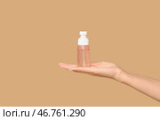 Молодая женщина с бутылкой очищающего средства на коричневом фоне. Стоковое фото, фотограф Pixel_shot / Фотобанк Лори