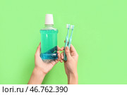 Женские руки с устным полосканием и зубными щетками на зеленом фоне. Стоковое фото, фотограф Pixel_shot / Фотобанк Лори