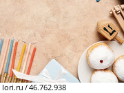Композиция Хануки с пончиками, свечами, подарочной коробкой и вращающейся игрушкой на бежевом столе, крупным планом. Стоковое фото, фотограф Pixel_shot / Фотобанк Лори