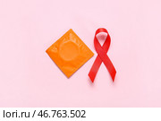 Красная лента с презервативом на розовом фоне. Концепция Дня борьбы со СПИДом. Стоковое фото, фотограф Pixel_shot / Фотобанк Лори