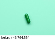 Зеленая медицинская капсула на бирюзовом фоне. Стоковое фото, фотограф Pixel_shot / Фотобанк Лори