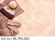 Пара вязанных варежек с теплой шапкой и шарфом на бежевом гранжевом фоне. Стоковое фото, фотограф Pixel_shot / Фотобанк Лори