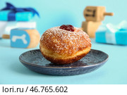 Вкусный пончик с каплевидными игрушками и подарочными коробками на голубом фоне. Празднование Хануки. Стоковое фото, фотограф Pixel_shot / Фотобанк Лори