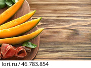 Вкусная дыня с прошутто на деревянном столе. Стоковое фото, фотограф Pixel_shot / Фотобанк Лори