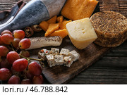 Ассорти из вкусных сыров с бутылкой вина на столе. Стоковое фото, фотограф Pixel_shot / Фотобанк Лори