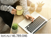 Молодая женщина, использующая ноутбук и пьющая кофе дома. Стоковое фото, фотограф Pixel_shot / Фотобанк Лори