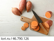 Доска с сырым резаным бататом и ножом на деревянном столе. Стоковое фото, фотограф Pixel_shot / Фотобанк Лори