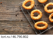 Охлаждающая подставка с вкусными луковыми кольцами на деревянном столе. Стоковое фото, фотограф Pixel_shot / Фотобанк Лори
