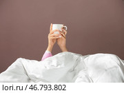 Сонная женщина под одеялом с чашкой кофе в постель. Стоковое фото, фотограф Pixel_shot / Фотобанк Лори