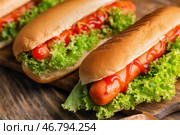Вкусные хот-доги с салатом на деревянном столе, крупным планом. Стоковое фото, фотограф Pixel_shot / Фотобанк Лори