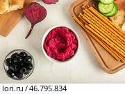 Композиция с вкусным хумусом из свеклы, оливками и хлебными палочками на светлом фоне. Стоковое фото, фотограф Pixel_shot / Фотобанк Лори