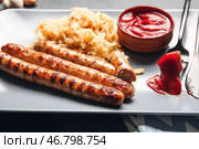 Тарелка с вкусной квашеной капустой, жареными сосисками и соусом, крупным планом. Стоковое фото, фотограф Pixel_shot / Фотобанк Лори
