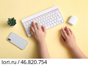 Женщина-программист работает за компьютерной клавиатурой с мобильным телефоном и наушниками на бежевом фоне. Стоковое фото, фотограф Pixel_shot / Фотобанк Лори