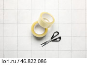 Рулончики клейкой ленты и канцелярские ножницы на белом кафельном фоне. Стоковое фото, фотограф Pixel_shot / Фотобанк Лори