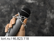 Деревянная рука с микрофоном и цепями на темном фоне, крупным планом. Концепция цензуры. Стоковое фото, фотограф Pixel_shot / Фотобанк Лори