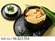 Миска вкусной сметаны с нарезанным зеленым луком и картофельными чипсами на желтом фоне. Стоковое фото, фотограф Pixel_shot / Фотобанк Лори
