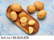 Деревянная доска с кусочками сырых маленьких картофелин на голубом фоне. Стоковое фото, фотограф Pixel_shot / Фотобанк Лори